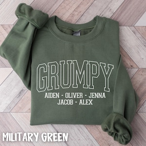 May include: Military green sweatshirt with the word "GRUMPY" in white block letters. Below the word "GRUMPY" are the names Aiden, Oliver, Jenna, Jacob, and Alex. The sweatshirt is made of a soft material.
