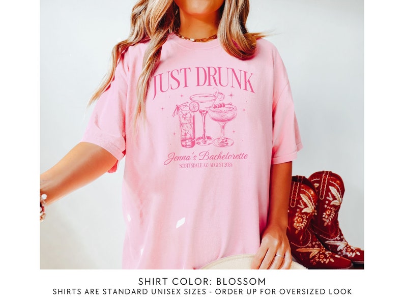 May include: Pink t-shirt with the text "JUST DRUNK" and a graphic of three cocktails. The text "Jenna's Bachelorette Scottsdale AZ August 2024" is below the graphic. The shirt colour is blossom.