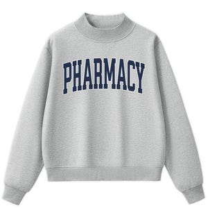 May include: A heather gray long-sleeve sweatshirt with a mock neck collar. The front features the word PHARMACY printed in a dark navy blue collegiate-style font. The garment has ribbed cuffs and a ribbed hem, providing a structured fit.