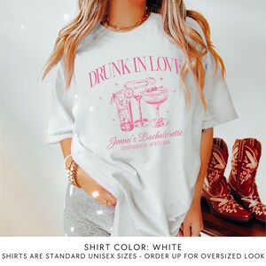 May include: White t-shirt with pink text that reads "Drunk in Love" and a graphic of two cocktails. The text below the graphic reads "Jenna's Bachelorette" and "Scottsdale, AZ August 2023".