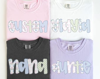 May include: Four t-shirts with different colors and patchwork designs. The shirts have the words "custom", "y'all", "mama", and "auntie" written on them.