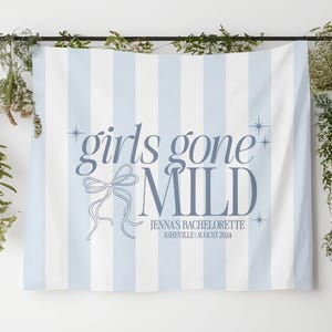 May include: A blue and white striped banner with the text "girls gone mild" in blue lettering. The banner also includes a decorative bow and the text "Jenna's Bachelorette Asheville | August 2024".