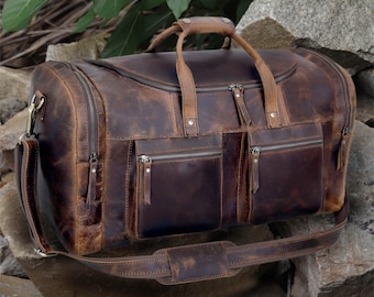 May include: A brown leather duffel bag with multiple pockets and a long shoulder strap. The bag has a distressed look and is made of high-quality leather.