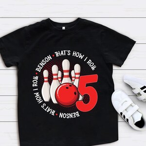 May include: Black t-shirt with a red and white bowling ball graphic and the text "Benson That's How I Roll That's How I Roll Benson" and the number 5.