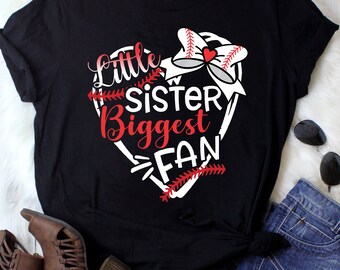 May include: Black t-shirt with a white heart design. The heart has a baseball and a red bow. The text "Little Sister Biggest Fan" is inside the heart.