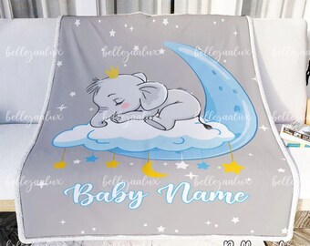 May include: A gray baby blanket with a blue crescent moon and a sleeping elephant on a cloud. The blanket has a white border and is decorated with stars and moons. The text "Baby Name" is printed in blue on the blanket.