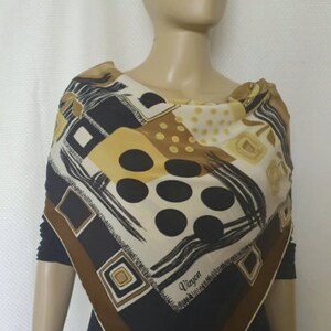 May include: A square silk scarf with a geometric pattern in black, brown, cream, and gold. The scarf features squares, circles, and brushstroke designs. The word "Vieyon" is printed on the scarf.