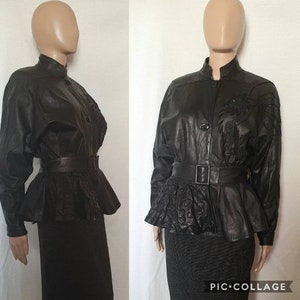 May include: Black leather jacket with a high collar, button closure, and a belted waist. The jacket features decorative embroidery on the shoulders and a peplum-style hem. The jacket is displayed on a mannequin.