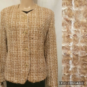 May include: A tan tweed jacket with a woven pattern of tan, white, and brown threads. The jacket has a round neckline, long sleeves, and four beige buttons down the front. The fabric has a textured appearance.