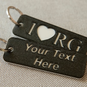 May include: Black and silver keychain with two tags. The top tag has a white heart with the text "I ♥ ORG" and the bottom tag has the text "Your Text Here".