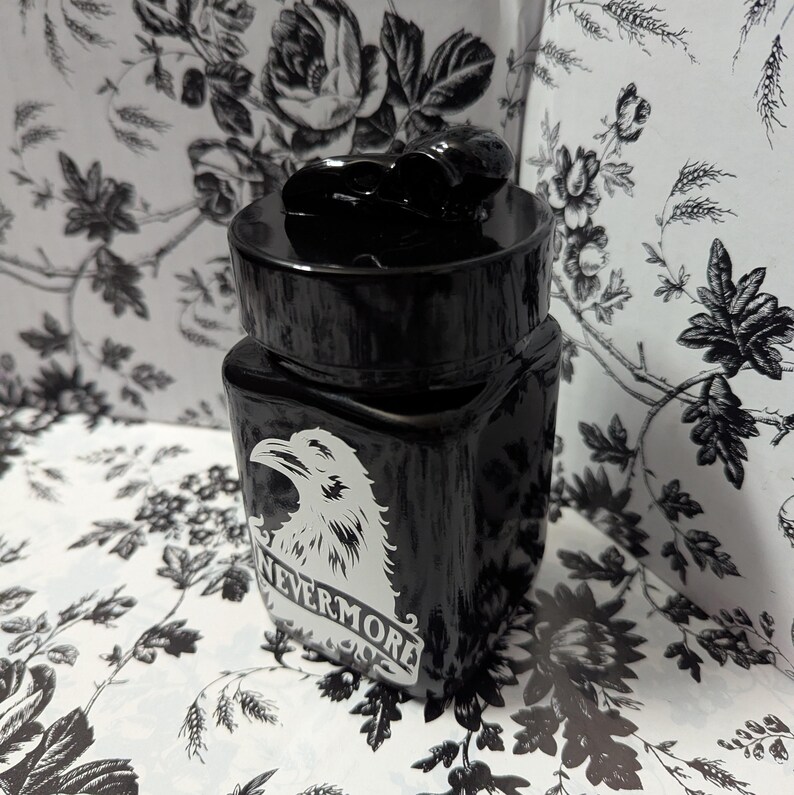 May include: Black glass jar with a black lid and a white raven graphic with the text "Nevermore" underneath.