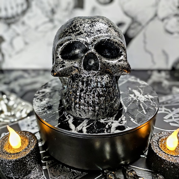 A gunmetal-and-black-splatter resin skull small enough to live on a shelf but striking enough to anchor a whole dark-aesthetic vignette.