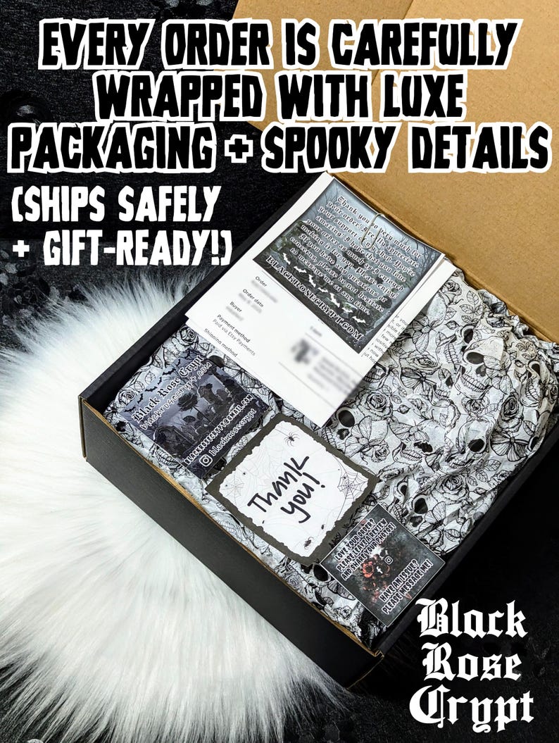 Op de afbeelding: Een zwarte doos met zwart-wit schedel- en rozenpatroon vloeipapier. De doos bevat een bon, een bedankkaart met een spinnenwebontwerp en andere kaarten. Tekst op de doos luidt "EVERY ORDER IS CAREFULLY WRAPPED WITH LUXE PACKAGING + SPOOKY DETAILS".
