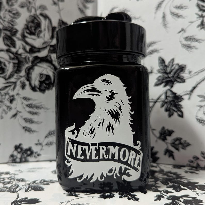 May include: Black glass jar with a white raven design and the text "Nevermore" on a banner.
