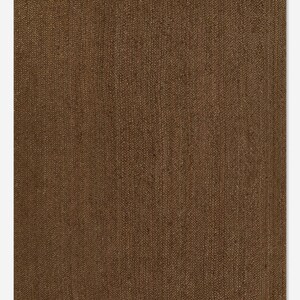 Puede incluir: Una alfombra rectangular marr&oacute;n con una textura tejida. La alfombra tiene un color s&oacute;lido y un dise&ntilde;o simple, adecuado para varios estilos de interior. La alfombra est&aacute; hecha de un material duradero.
