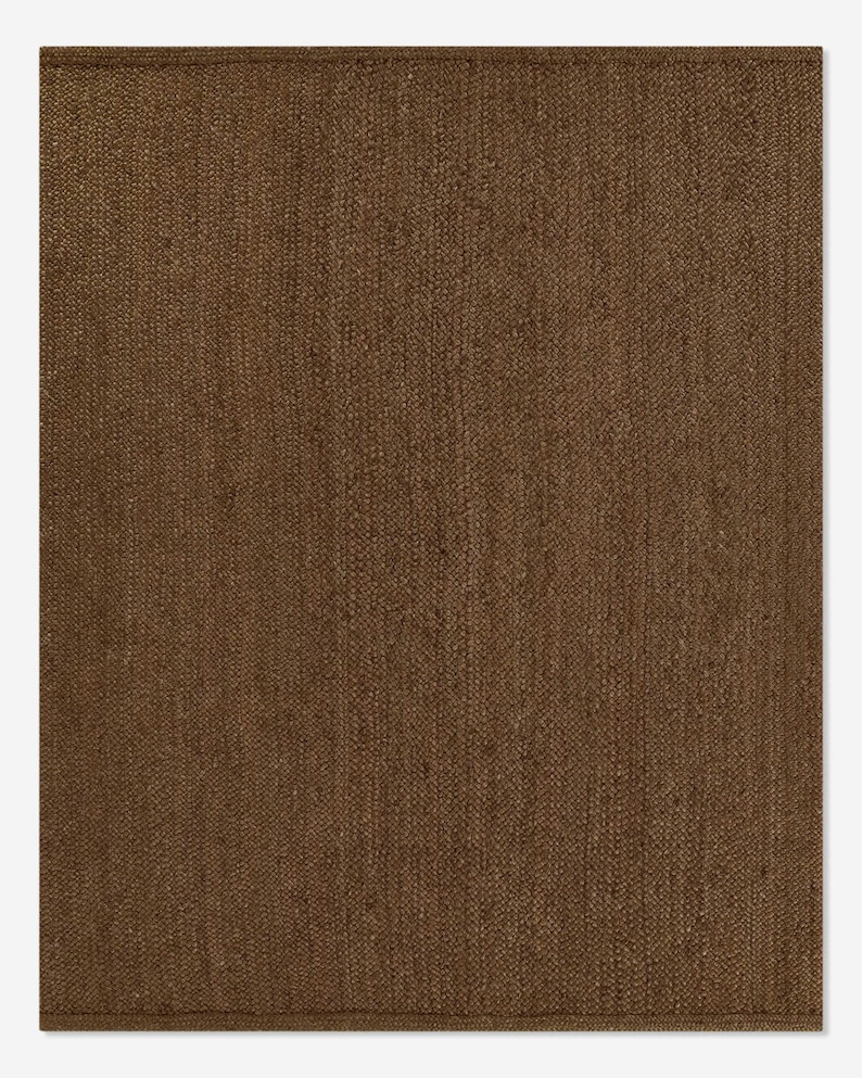 Puede incluir: Una alfombra rectangular marr&oacute;n con una textura tejida. La alfombra tiene un color s&oacute;lido y un dise&ntilde;o simple, adecuado para varios estilos de interior. La alfombra est&aacute; hecha de un material duradero.