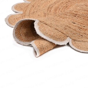 Pode incluir: Um tapete redondo de fibra natural com uma borda festonada. O tapete &eacute; feito de juta e tem uma bainha branca.