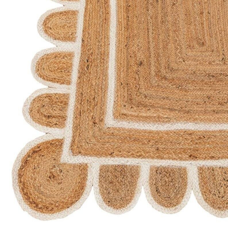 Puede incluir: Una alfombra cuadrada de yute con un borde blanco y un borde festoneado. La alfombra est&aacute; hecha de fibras naturales y tiene un aspecto r&uacute;stico y terroso.