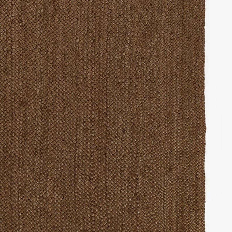 Puede incluir: Primer plano de una alfombra tejida marr&oacute;n con una superficie texturizada. La alfombra tiene un patr&oacute;n de tejido apretado y un tono c&aacute;lido y terroso. Las fibras de la alfombra son visibles, creando una apariencia t&aacute;ctil. La alfombra es adecuada para la decoraci&oacute;n del hogar.
