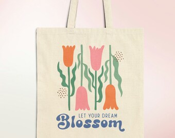 May include: A white canvas tote bag with a floral design featuring pink and orange tulips with green stems and leaves. The text "Let your dream blossom" is printed in blue on the bag.