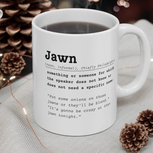 May include: White ceramic mug with a black definition of the word "Jawn" printed on it. The definition is from Philadelphia and says "something or someone for which the speaker does not know or does not need a specific name".