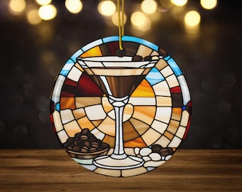 May include: A round, stained glass ornament featuring a martini glass filled with a brown liquid and coffee beans. The glass is surrounded by a colorful stained glass design with shades of blue, red, yellow, and brown.