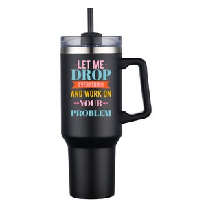 May include: Black stainless steel travel mug with a handle and a straw. The mug has a white, pink, blue, and orange design with the text "Let me drop everything and work on your problem."