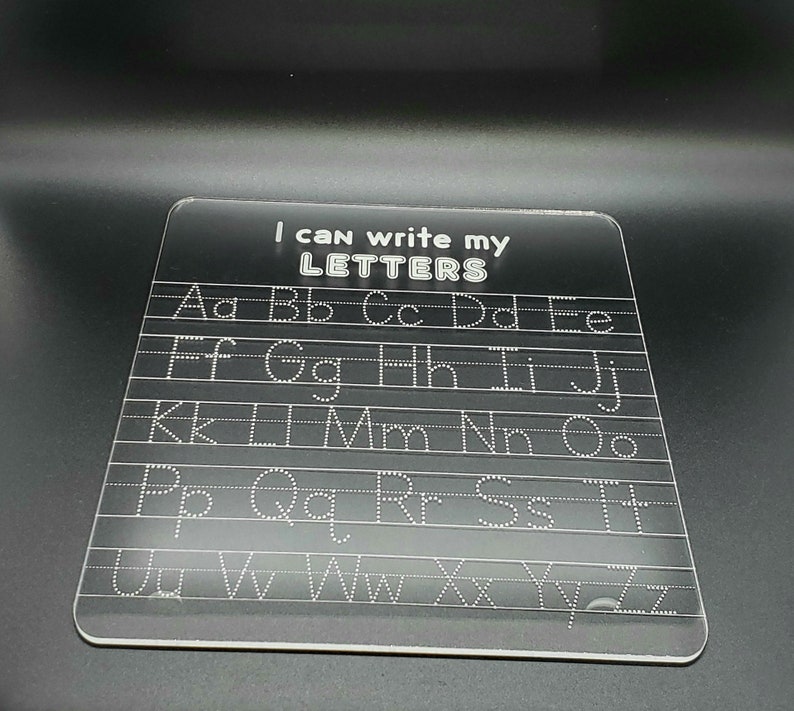 May include: A clear plastic dry-erase board with the text "I can write my LETTERS" at the top. The alphabet is written in rows with dotted lines for tracing.
