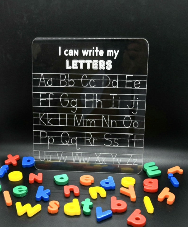 May include: A clear acrylic dry-erase board with the text "I can write my LETTERS" and dotted lines for tracing the alphabet.  The board is surrounded by colourful magnetic letters.