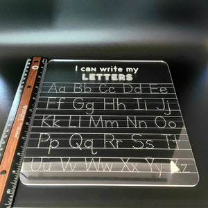 May include: A clear plastic dry-erase board with the text "I can write my LETTERS" at the top. The alphabet is written in rows with dotted lines for tracing.