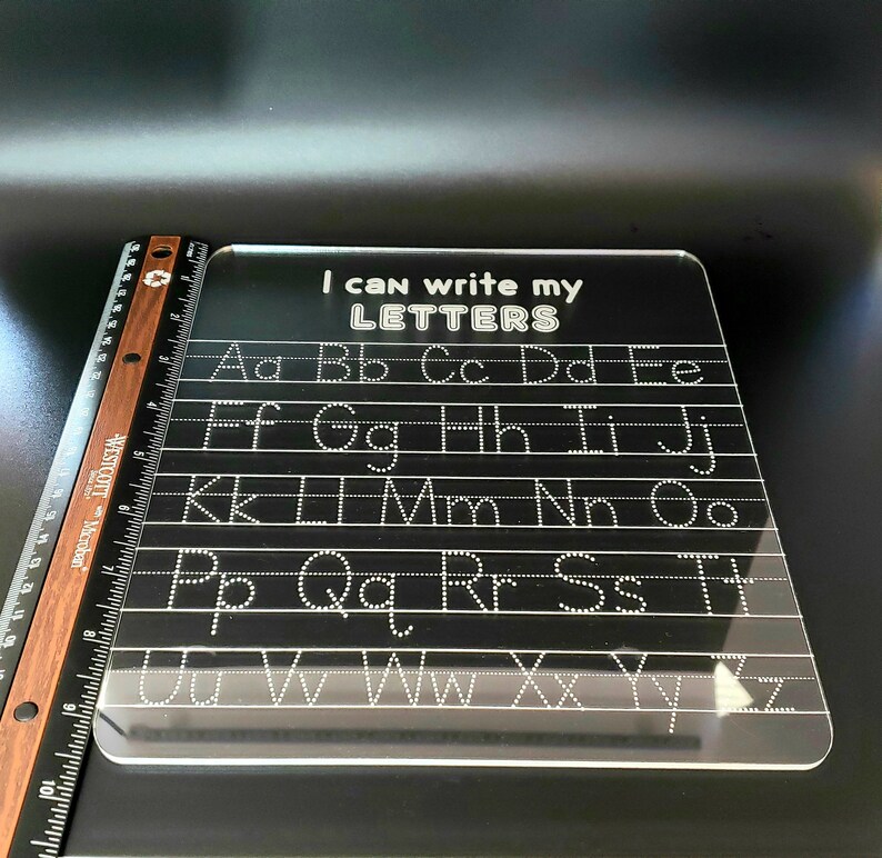 May include: A clear plastic dry-erase board with the text "I can write my LETTERS" at the top. The alphabet is written in rows with dotted lines for tracing.
