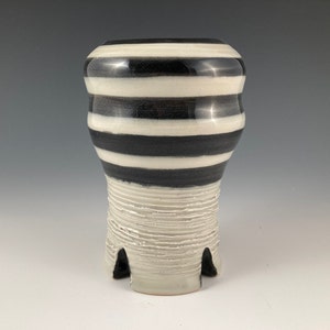 May include: A black and white striped ceramic vase with a textured base.