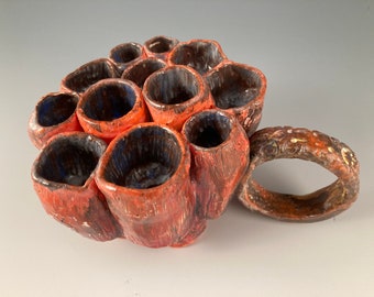 Taza de cerámica artística naranja con múltiples acanaladuras, abstracta y divertida