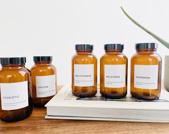 May include: Five amber glass bottles with black lids and white labels. The labels have the following text: Probiotic, Calcium, Multivitamin, Melatonin, and Ibuprofen.