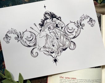 May include: Black and white illustration of a woman riding a unicorn, pierced by arrows. The artwork features ornate floral and star accents. The image is on a white background, with a book and fabric visible in the background.