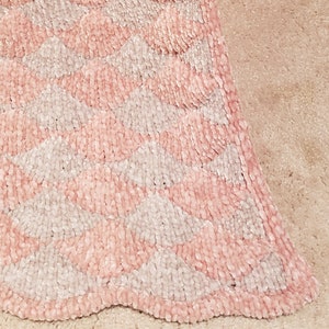 Pode incluir: Um cobertor de lançamento rosa e branco com um padrão chevron e uma textura macia e felpuda.