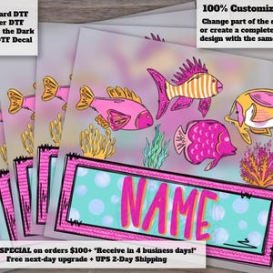 May include: A stack of rectangular decal sheets featuring a colorful underwater scene with pink, orange, and yellow fish, coral, and seaweed. A central turquoise rectangular frame contains the word NAME in large, bold, bright pink letters.