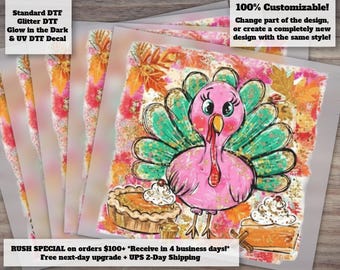 May include: A square transfer sheet featuring a cartoon turkey with a pink body and teal tail feathers, surrounded by autumn leaves and two pumpkin pies with whipped cream. The text reads: Standard DTF, Glitter DTF, Glow in the Dark & UV DTF Decal.