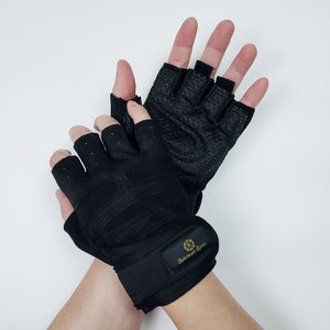 May include: A pair of black fingerless weightlifting gloves with a black wrist strap. The strap has the text "Basement Raw" in gold lettering.