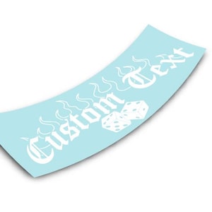 Op de afbeelding: Witte vinyl sticker met een vlamontwerp en de tekst "Custom Text" in een gotisch lettertype. Twee witte dobbelstenen zijn opgenomen in het ontwerp.
