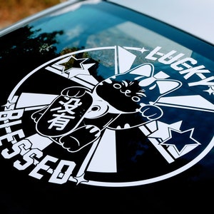 Op de afbeelding: Zwart-witte sticker met een gelukkat-ontwerp. De kat houdt een bord vast waarop "Lucky" in het Japans staat. De sticker zegt ook "Blessed" en "Lucky" in witte letters.