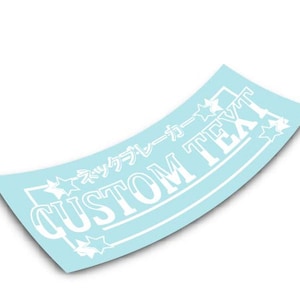 Op de afbeelding: Witte vinyl sticker op een blauwe achtergrond. De sticker heeft een witte rand en sterren rond de tekst "CUSTOM TEXT" en de Japanse tekst "ドリフトカー".