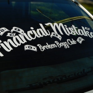 Op de afbeelding: Witte vinyl sticker voor een autoruit met de tekst "Financial Mistake" in een sierlijke lettertype, vergezeld van dollarbiljet illustraties. De tekst "Broken Boyz Club" is ook zichtbaar eronder.
