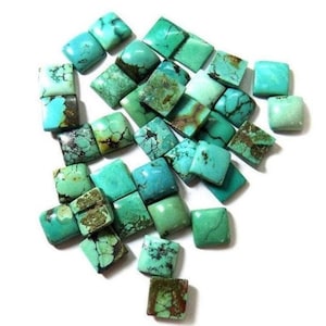 Può includere: Una collezione di cabochon di turchese, ognuno con una forma quadrata e una superficie liscia e lucida. Le pietre variano di colore da un verde-azzurro chiaro a un verde-azzurro scuro.