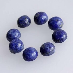 May include: Ten round, dark blue lapis lazuli cabochons with gold flecks. The cabochons are arranged in a circle on a white background.