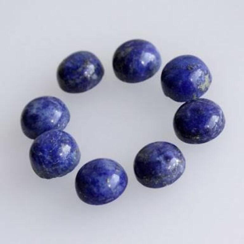 May include: Ten round, dark blue lapis lazuli cabochons with gold flecks. The cabochons are arranged in a circle on a white background.