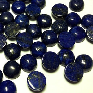 May include: A collection of round, dark blue lapis lazuli cabochons with gold flecks. The cabochons are smooth and polished, and they are arranged in a random pattern.