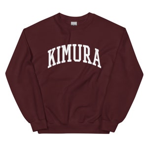 May include: A maroon sweatshirt with the word "KIMURA" printed in white in an arched font.