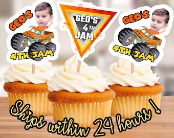 以下が含まれることがあります： モンスタートラックと「Geo's 4th Jam」の文字、そして子供の顔が描かれた、3つのカップケーキトッパー。トッパーは、白いフロスティングがかけられたカップケーキの上に置かれています。