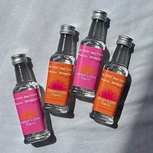 May include: Four clear glass bottles with pink and orange labels that say "Sunset Bday Cruise Tequila Norwegian" and "Ashley's 25th Tequila".